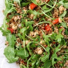 Rye berry salad with roasted peppers and arugula on a platter