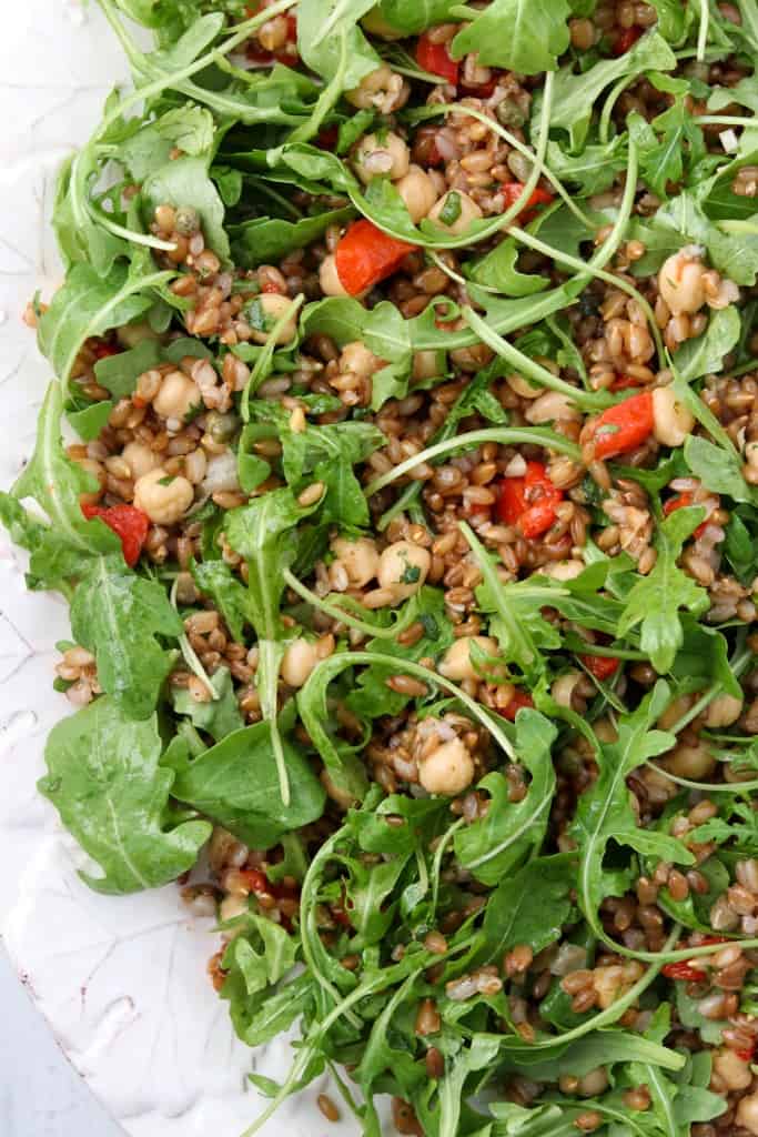 Rye berry salad with roasted peppers and arugula on a platter