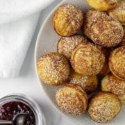 Æbleskivers on a plate next to jam and a napkin.