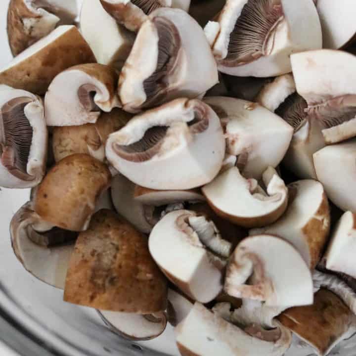 Raw mushrooms in a glass bowl.
