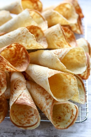 Krumkaker piled onto a wire cooling rack.