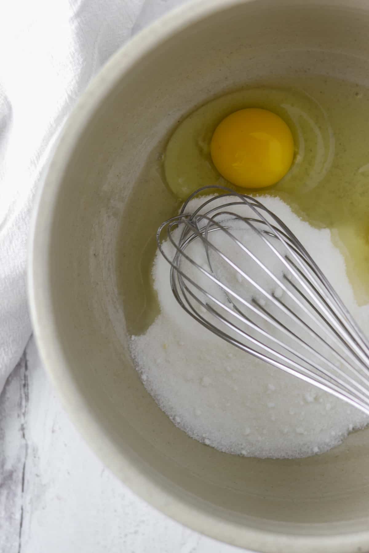 Sugar and egg in a bowl with a whisk.