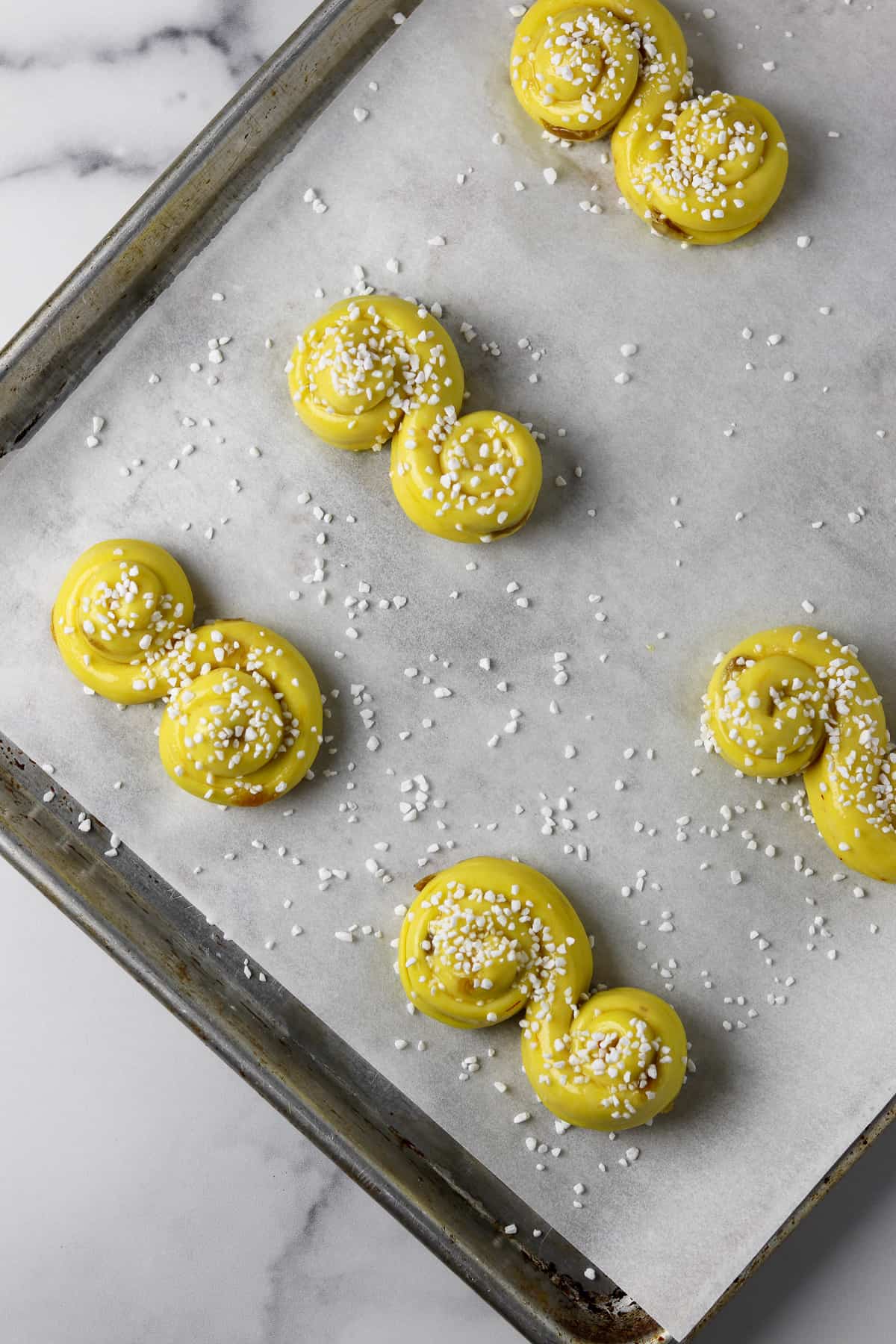 St. Lucia Buns sprinkled with sugar on a sheet pan.