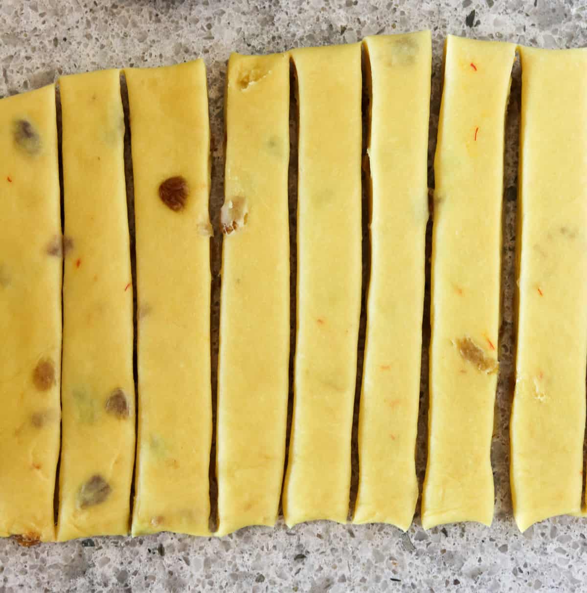 Strips of saffron dough on a gray countertop