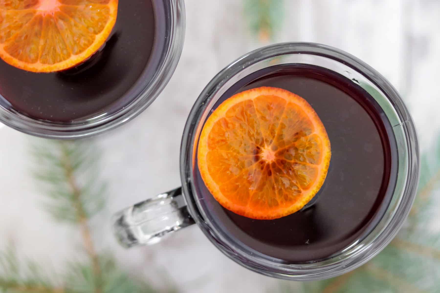 Close up of a cup of mulled wine with an orange slice floating on top.