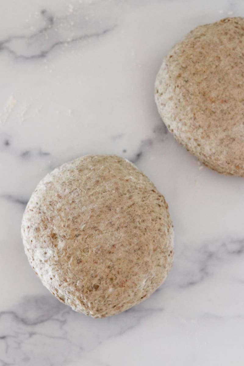 Bread dough rounds on a marble surface.