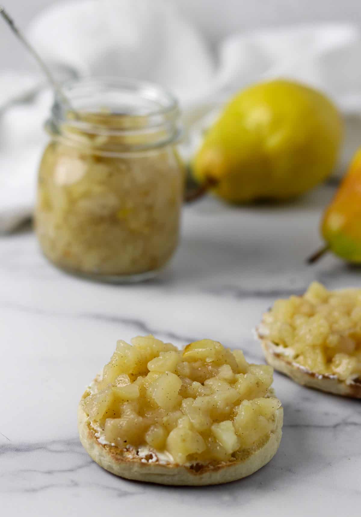 Pear compote on an English muffin on a marble surface.