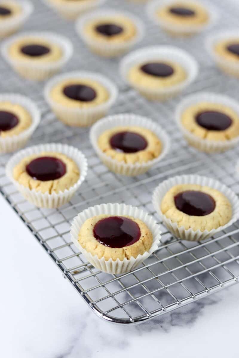 Raspberry thumbprint cookies on a cooling rack.