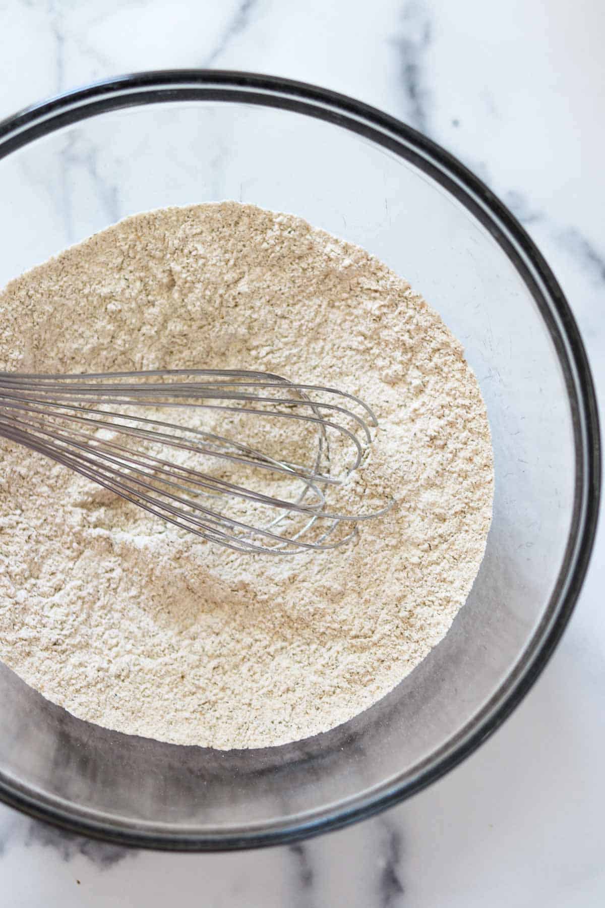 Flour and a whisk in a glass bowl.