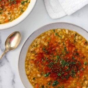Two bowls of split pea soup next to a spoon and napkin.