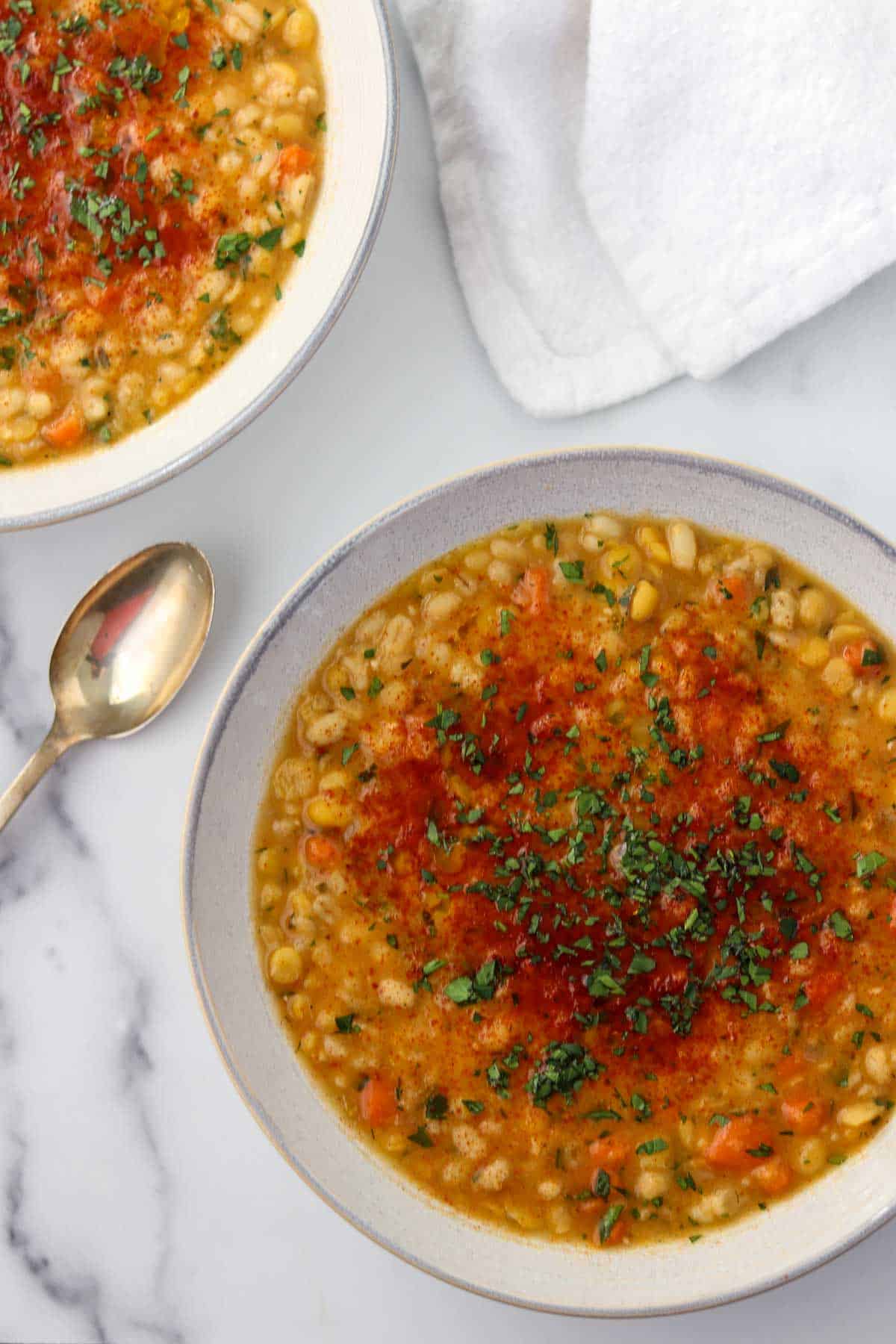 Two bowls of split pea soup next to a spoon and napkin.