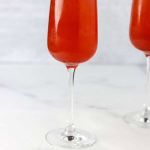 Champagne glass filled with Swedish 75 cocktail next to lingonberries.