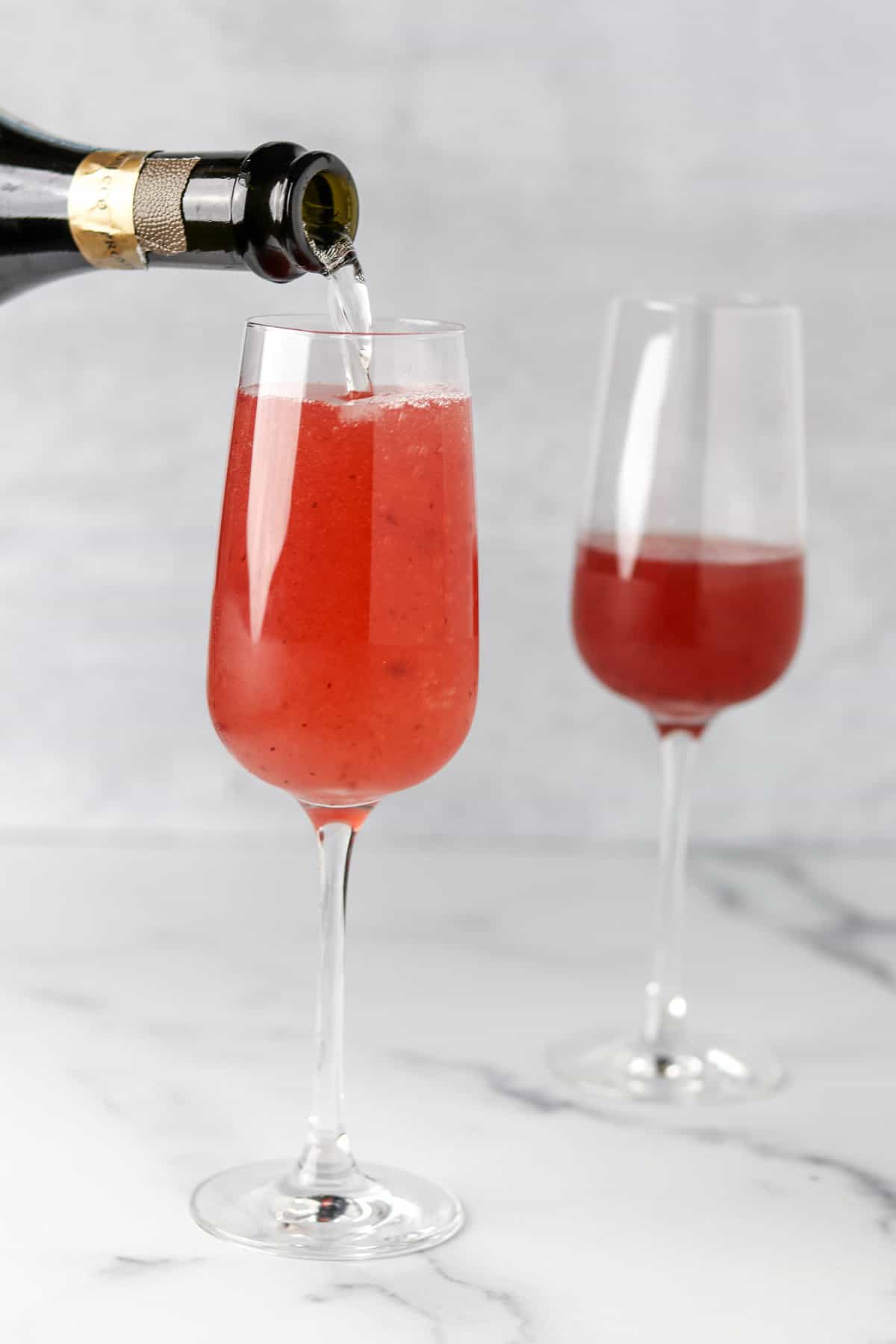 Person pouring sparkling wine into a champagne glass.