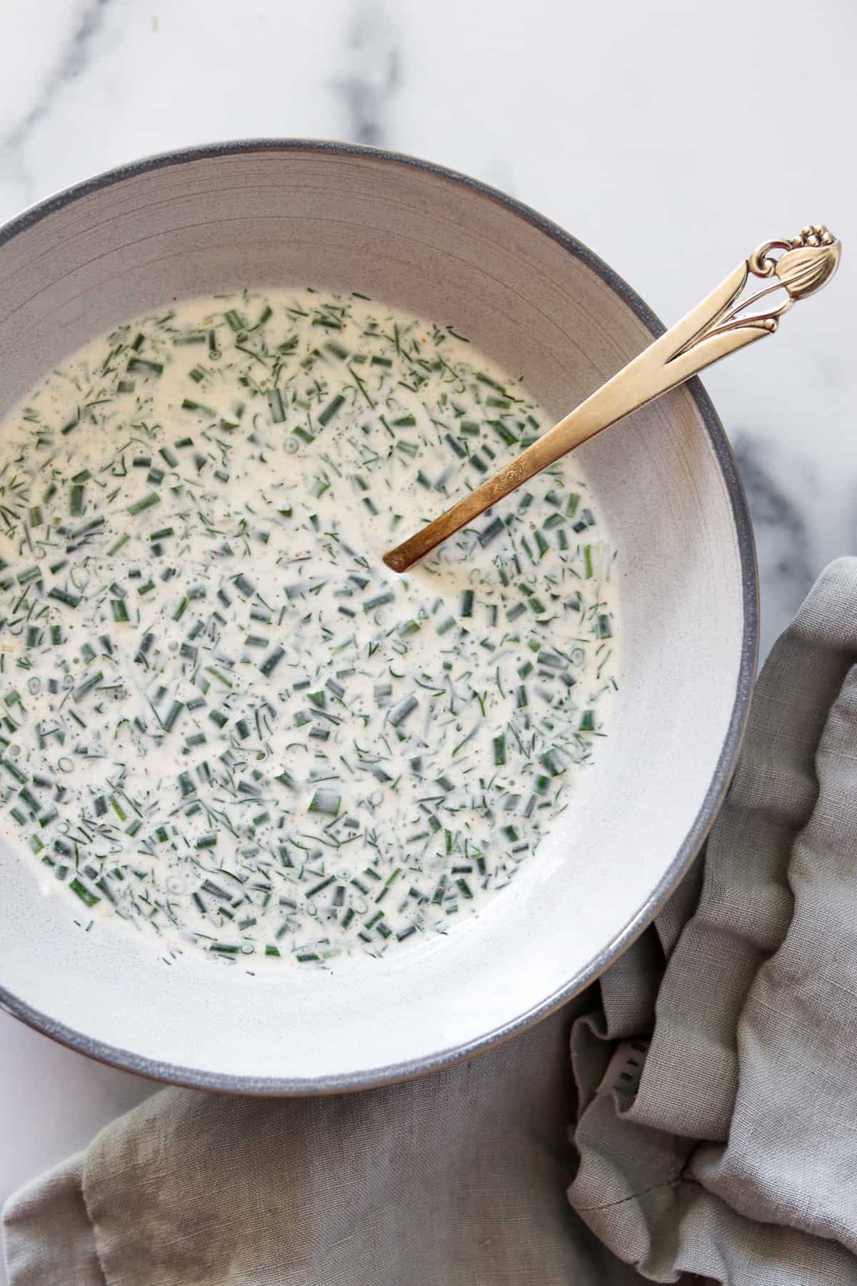 Creamy herbed skyr sauce in a bowl with a spoon.