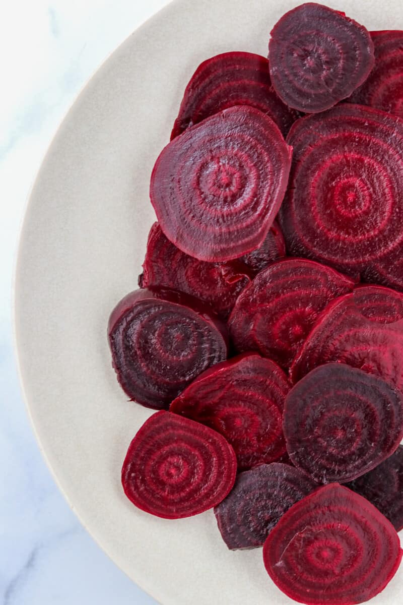 Roasted and sliced beets on a white plate.