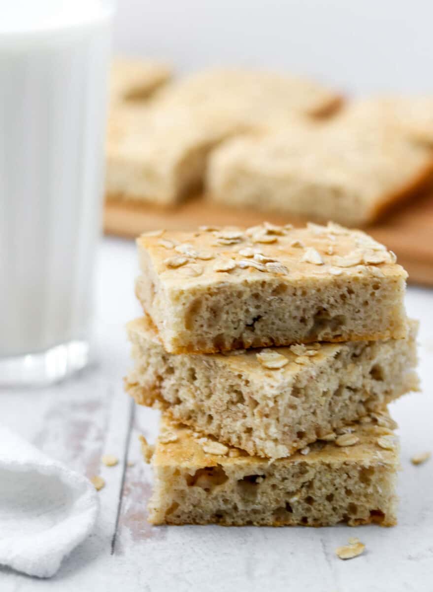 Squares of Finnish flat bread stacked on top of each other next to a glass of milk.