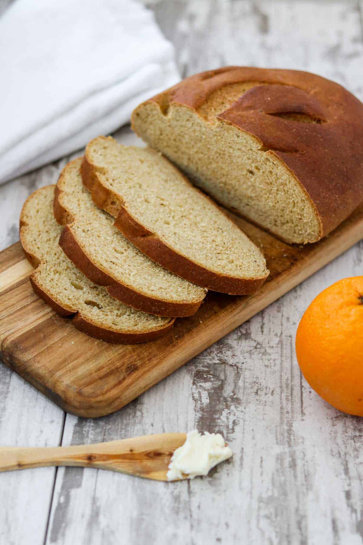 Swedish limpa bread on a cutting board next to butter and an orange.