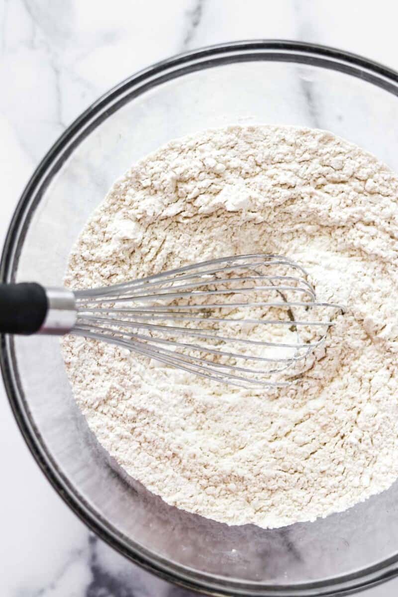 Flour in a glass bowl with a whisk.