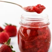 Jar of Roasted Strawberry Rhubarb Compote with a spoon next to strawberries.