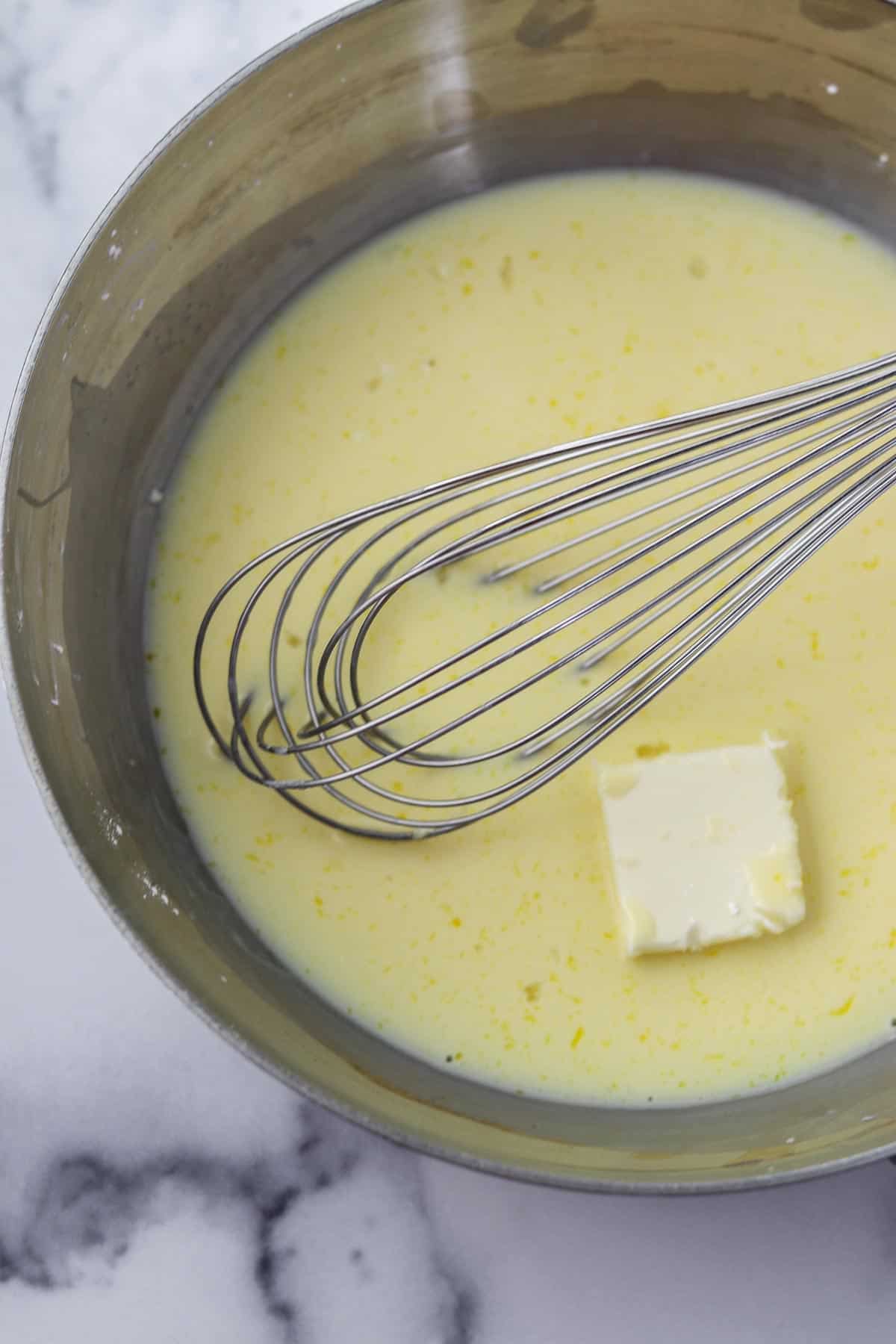 Eggs, milk and butter in a pan with a whisk.