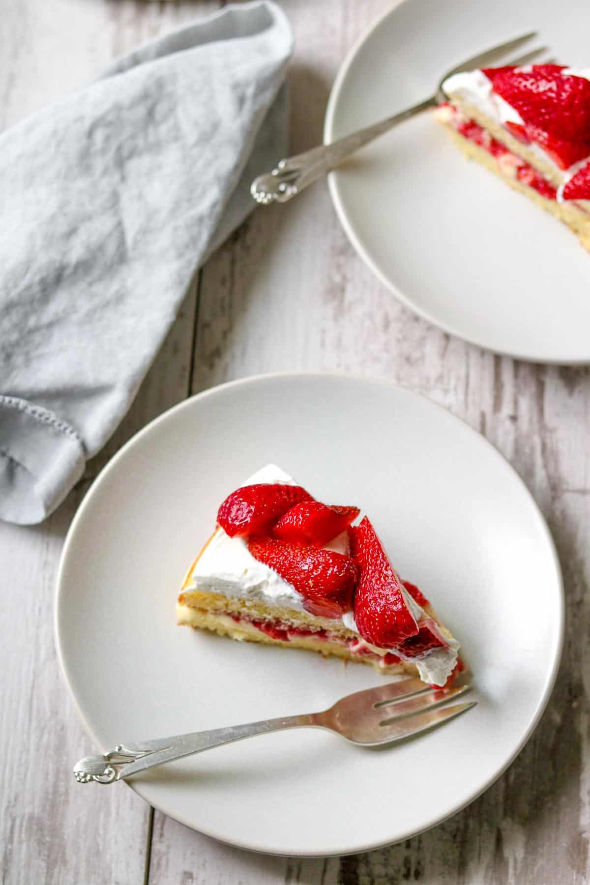 Slice of Scandinavian Strawberry Cream Cake next to a fork and napkin.