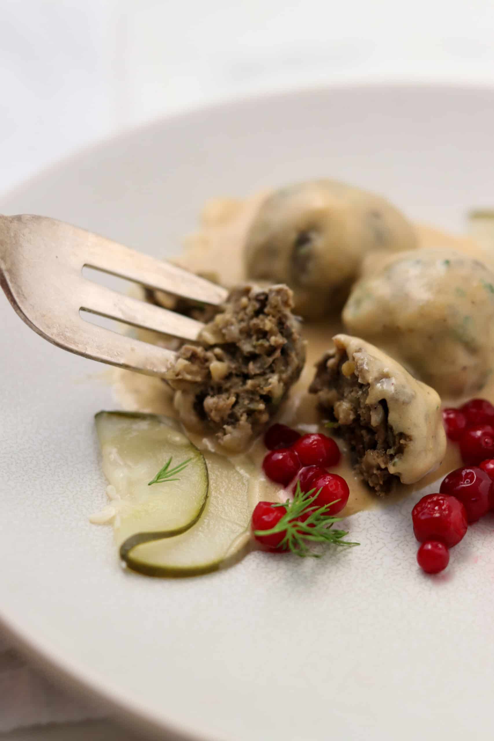 Close up of Vegetarian Swedish Meatballs with pickles and lingonberries.