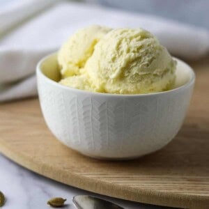 Cardamom Ice Cream in a white dish on a wooden surface.
