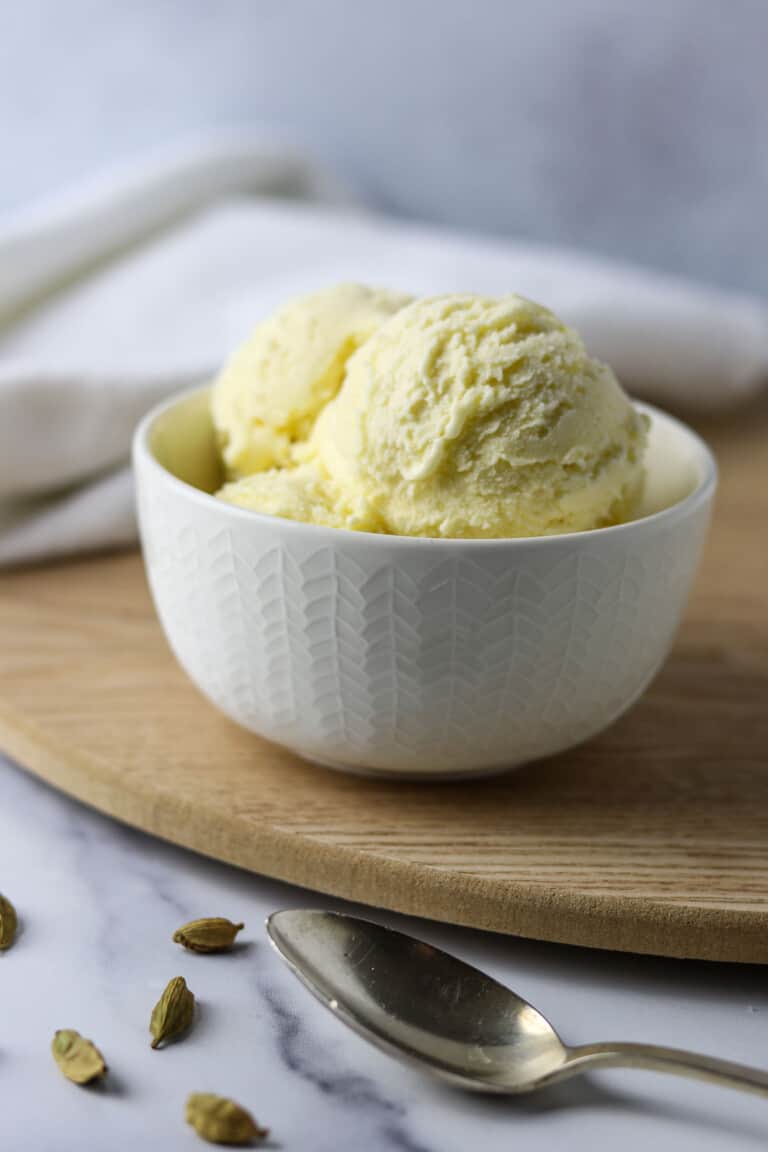 Cardamom Ice Cream in a white dish on a wooden surface.