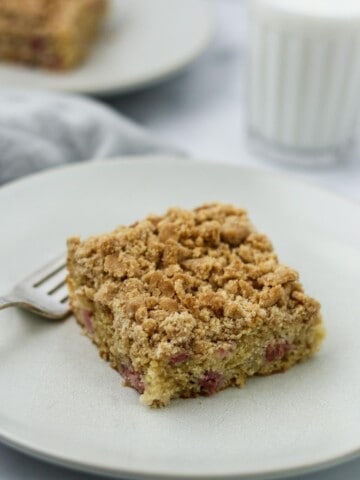 Old-Fashioned Norwegian Rhubarb Crumb Cake on a plate next to a glass of milk.