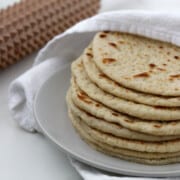 Soft Swedish Flatbreads on a plate next to a towel and a spiky rolling pin.
