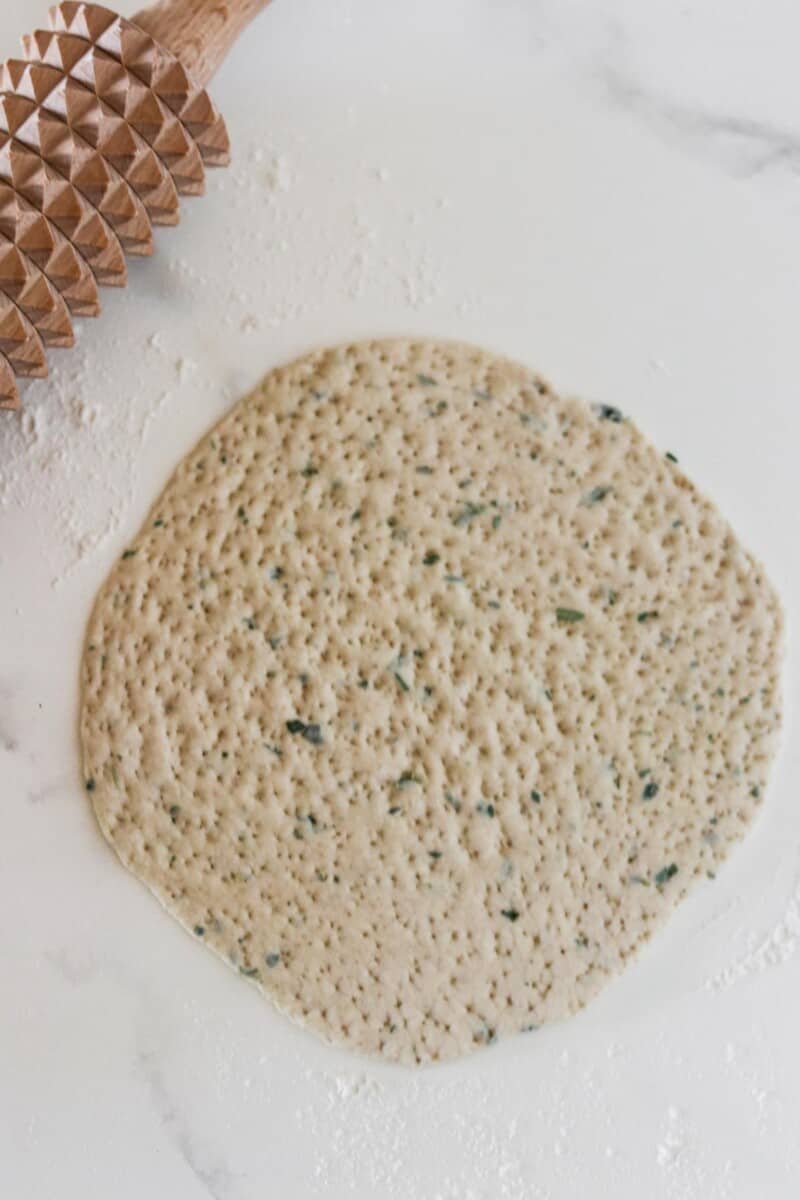 Rolled out flatbead dough with herbs.