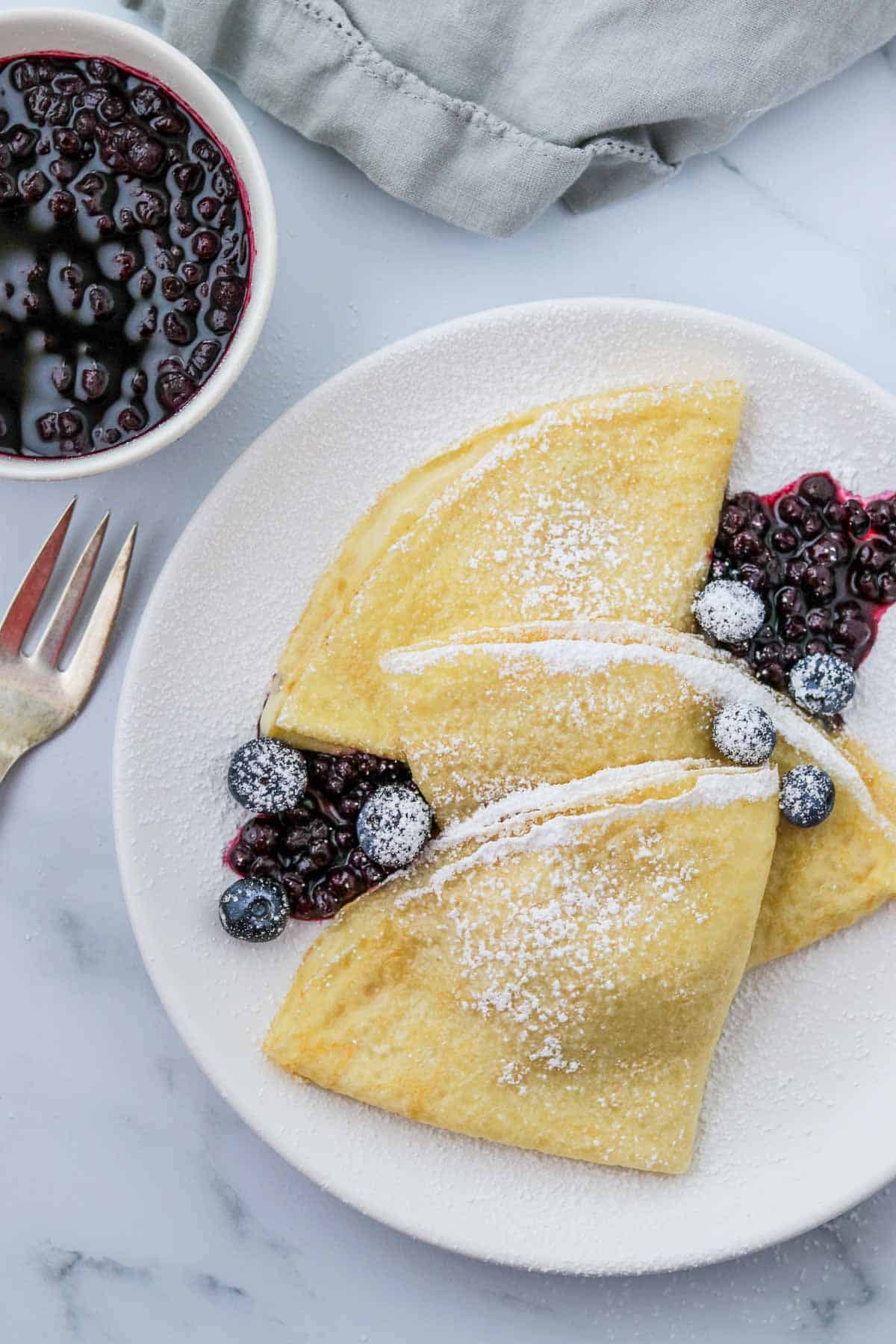 Swedish pancakes topped with blueberries and powdered sugar.