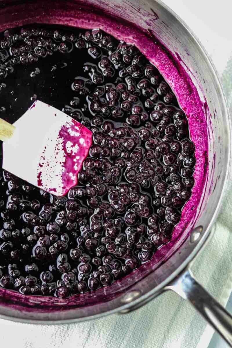 Blueberry compote in a saucepan with a rubber spatula