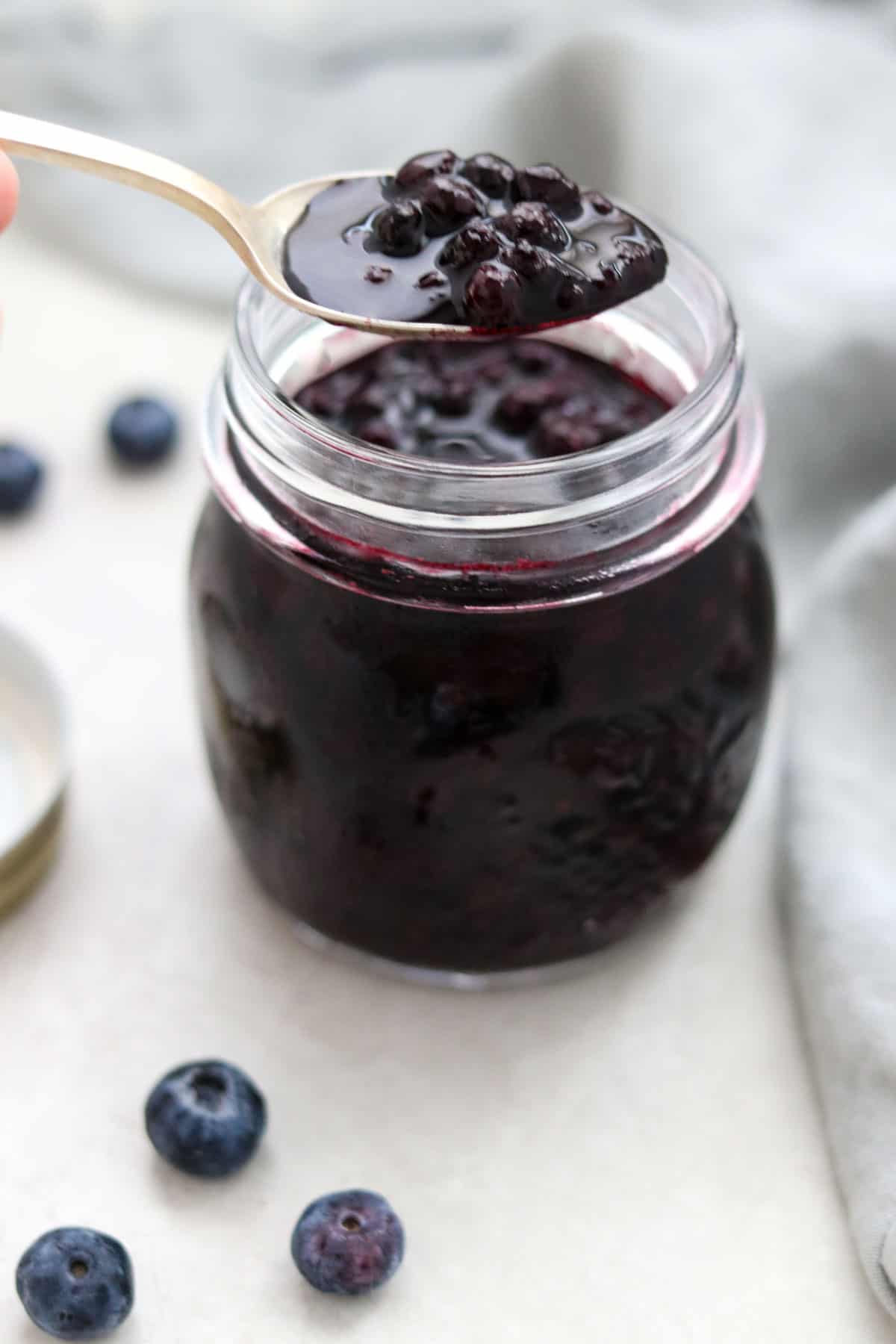 Blueberry Cardamom Compote in a jar next to blueberries.