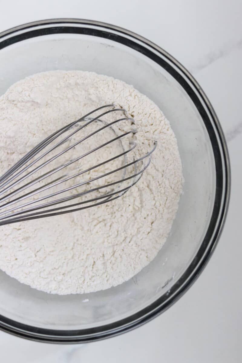 Flour in a glass bowl with a whisk.
