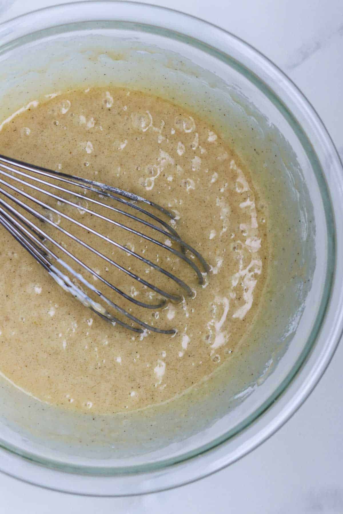 Apple cake batter in a bowl with a whisk.