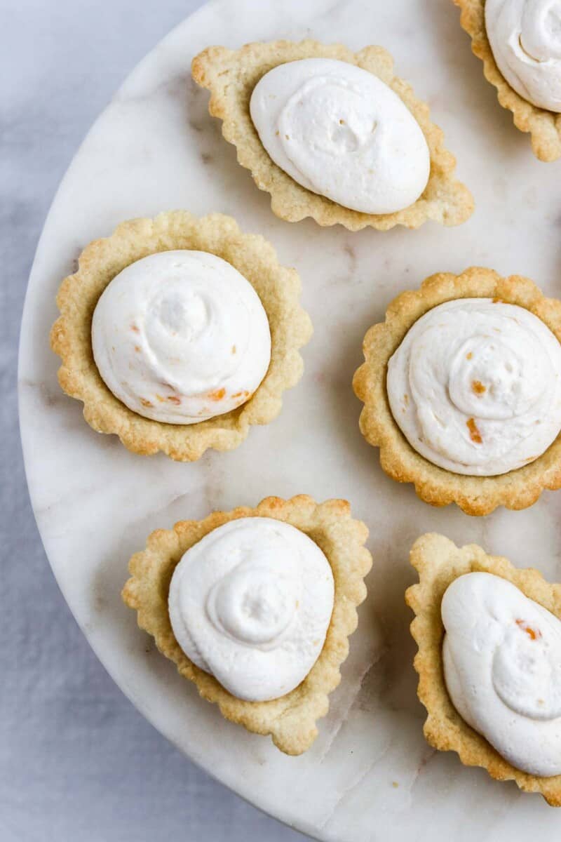 Scandinavian Almond Tarts filled with Cloudberry Cream on a marble surface.