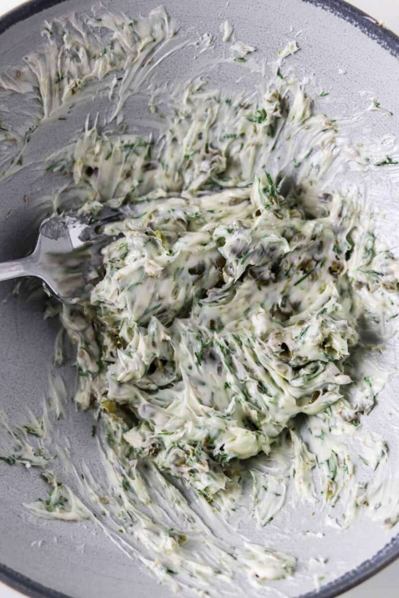 Dill Caper Butter being stirred with a fork in a bowl.