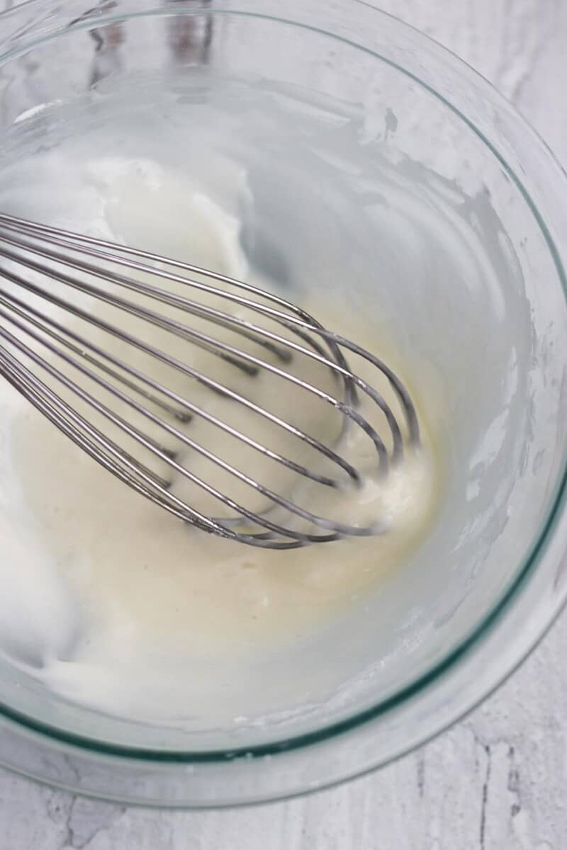 Lemon glaze in a bowl with a whisk.