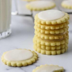 A stack of Nordic Lemon Wafers on a marble surface next to a glass of milk.