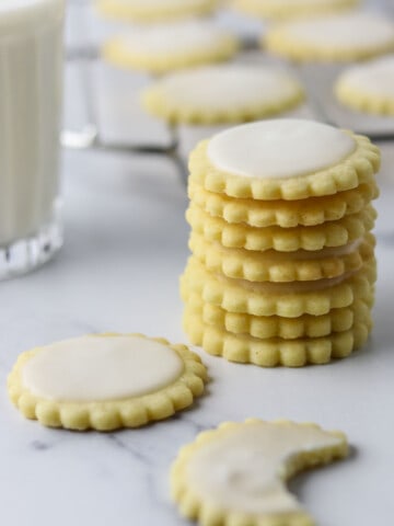 A stack of Nordic Lemon Wafers on a marble surface next to a glass of milk.