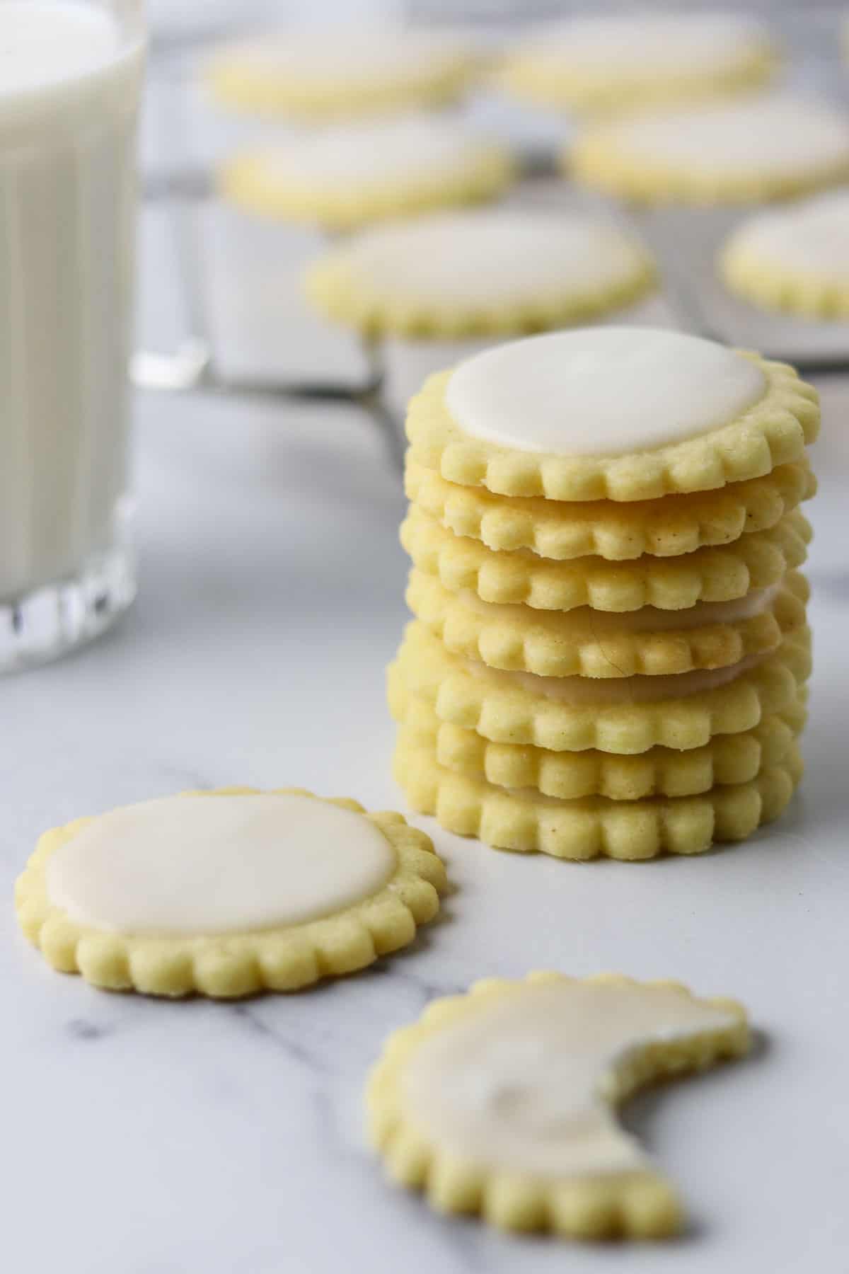 A stack of Nordic Lemon Wafers on a marble surface next to a glass of milk.