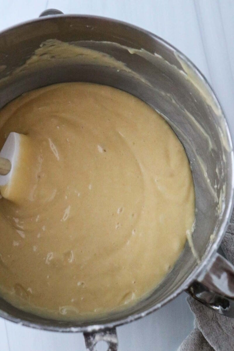 Vanilla cake batter in a metal bowl with a rubber spatula.