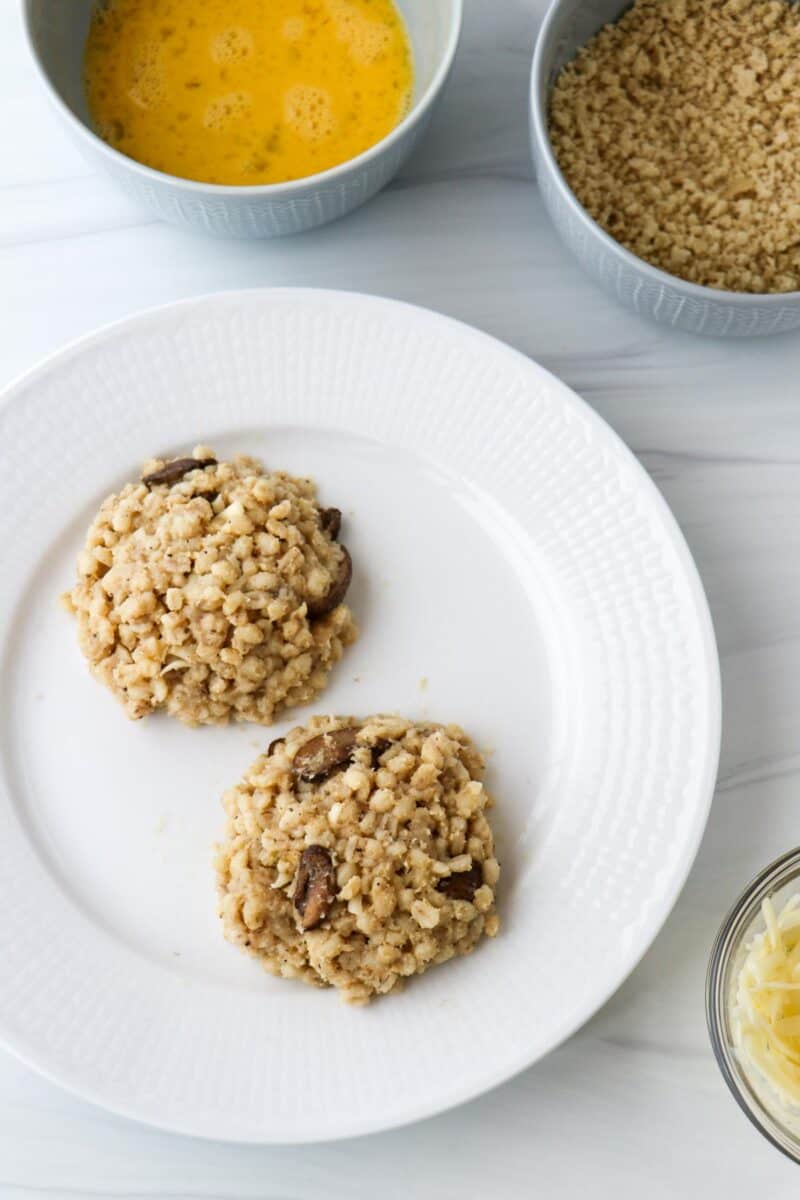 Uncooked and uncoated barley risotto cakes on a plate.