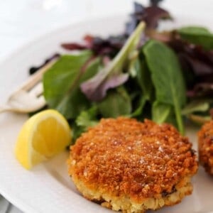 Cripsy Barley Risotto Cake next to a lemon wedge and salad.