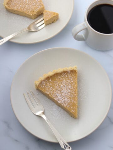 Brown Sugar Skyr Tart on a plate next to a cup of coffee.