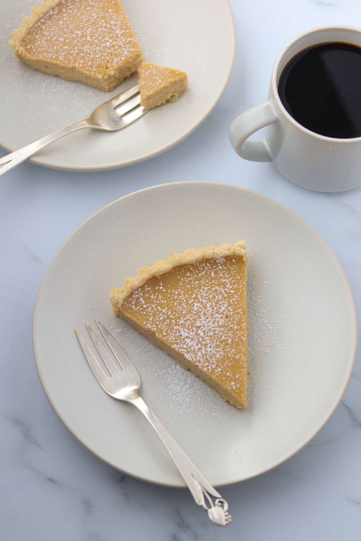 Brown Sugar Skyr Tart on a plate next to a cup of coffee.