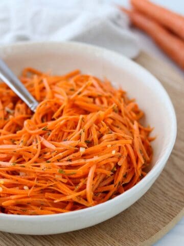 Nordic Carrot Salad with Lemon and Dill in a bowl next to two carrots.