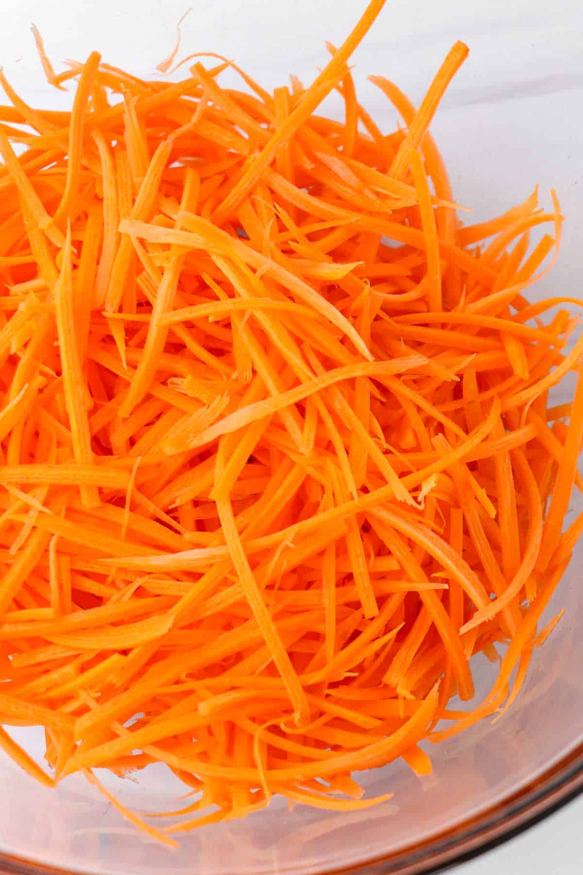 Shredded carrots in a glass bowl.