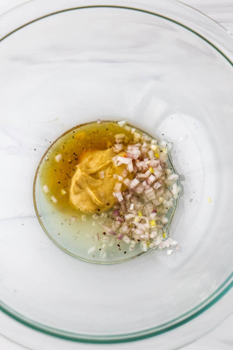 Chopped shallot, mustard and honey in a glass bowl.